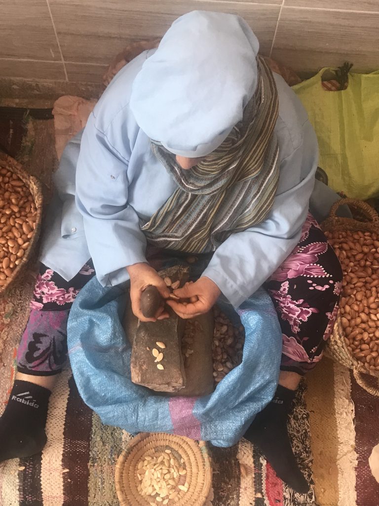 Woman cracking Argan nuts at Cooperative Tirizite Arazane Morocco - by Khadija Fajry