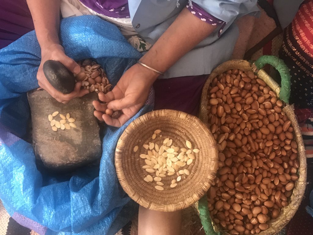 Woman cracking Argan nuts at Cooperative Tirizite Arazane Morocco - by Khadija Fajry